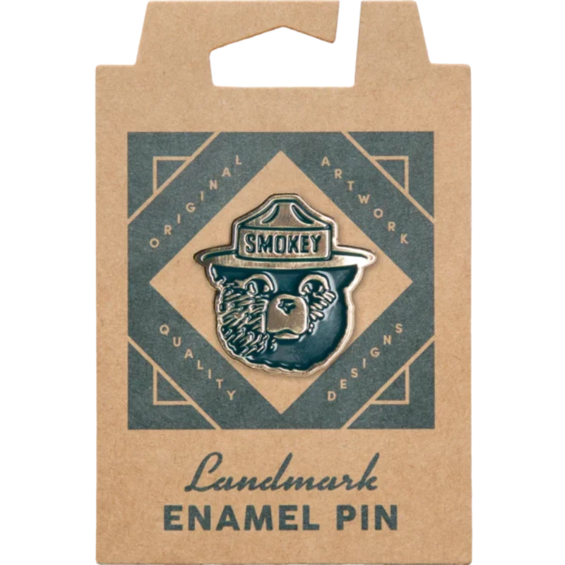 Smokey Bear enamel pin mounted on an illustrated kraft backing card